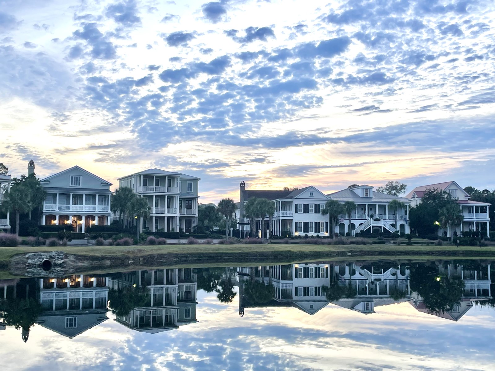 Row of homes reflected in a pond under a morning sky
