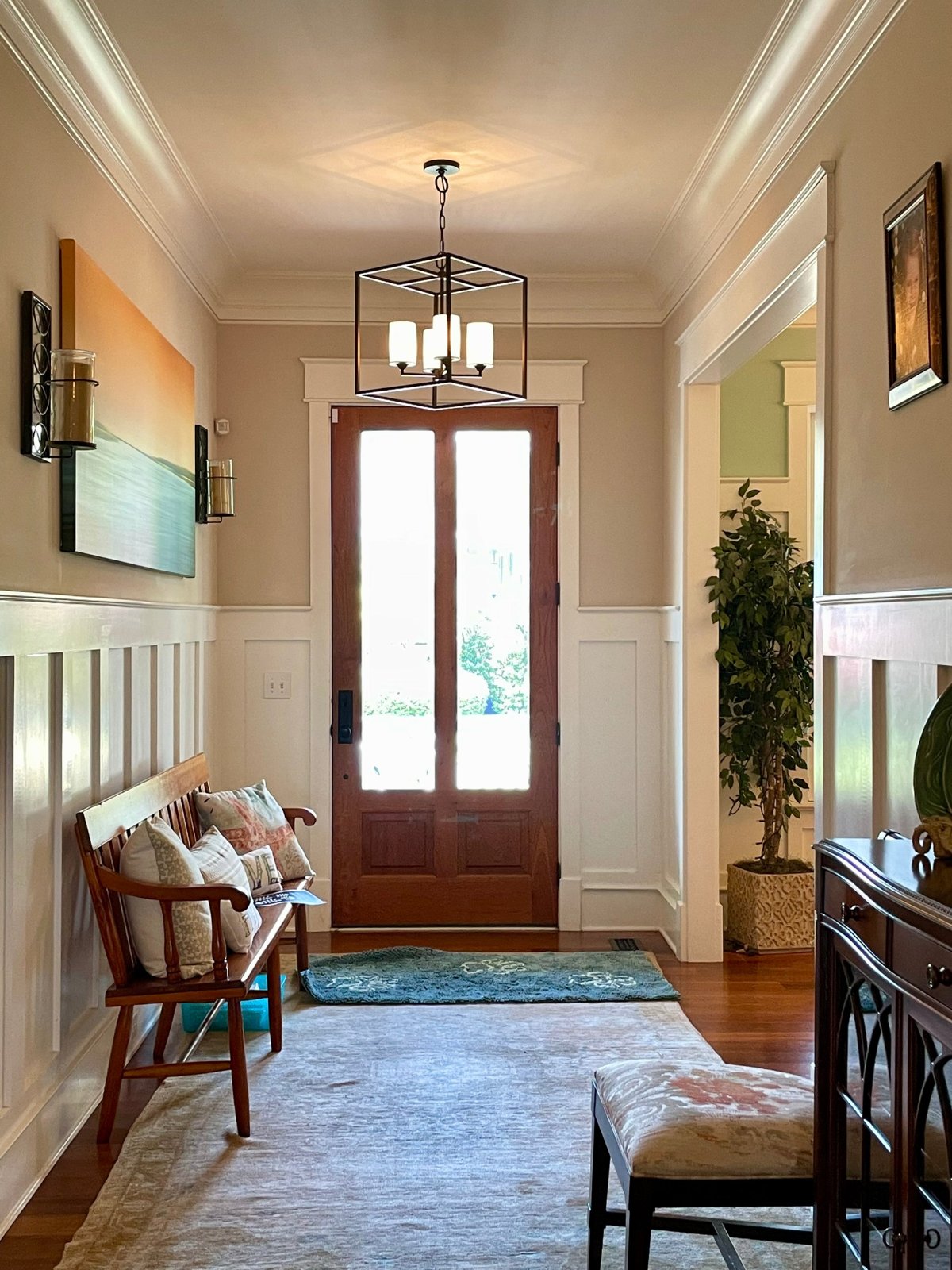 Bright entry hall with a wood front door, bench and lantern pendant light