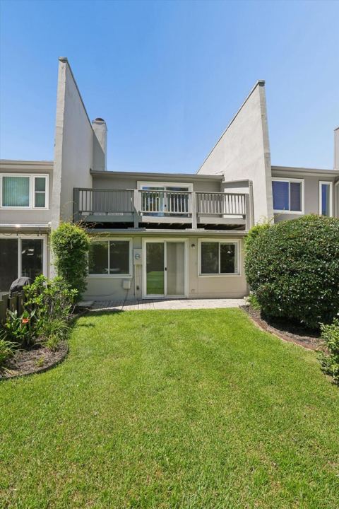Back of the home with the lawn and upstairs deck